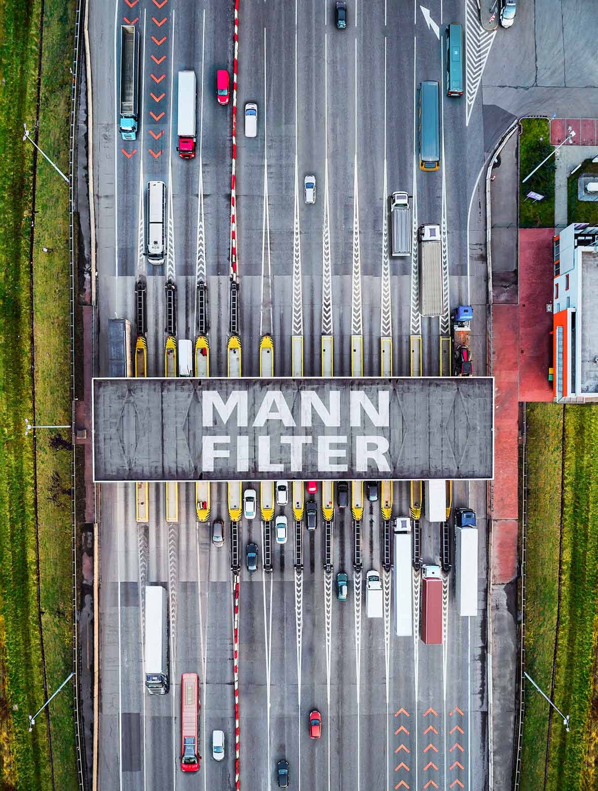 Draufsicht auf eine Mautstation mit MANN-FILTER-Branding, umgeben von Lkw und Bussen