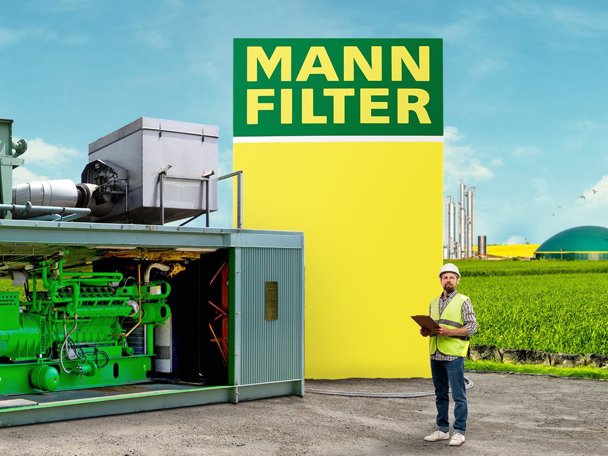 A man in a safety vest beside a green industrial generator and a large MANN-FILTER box