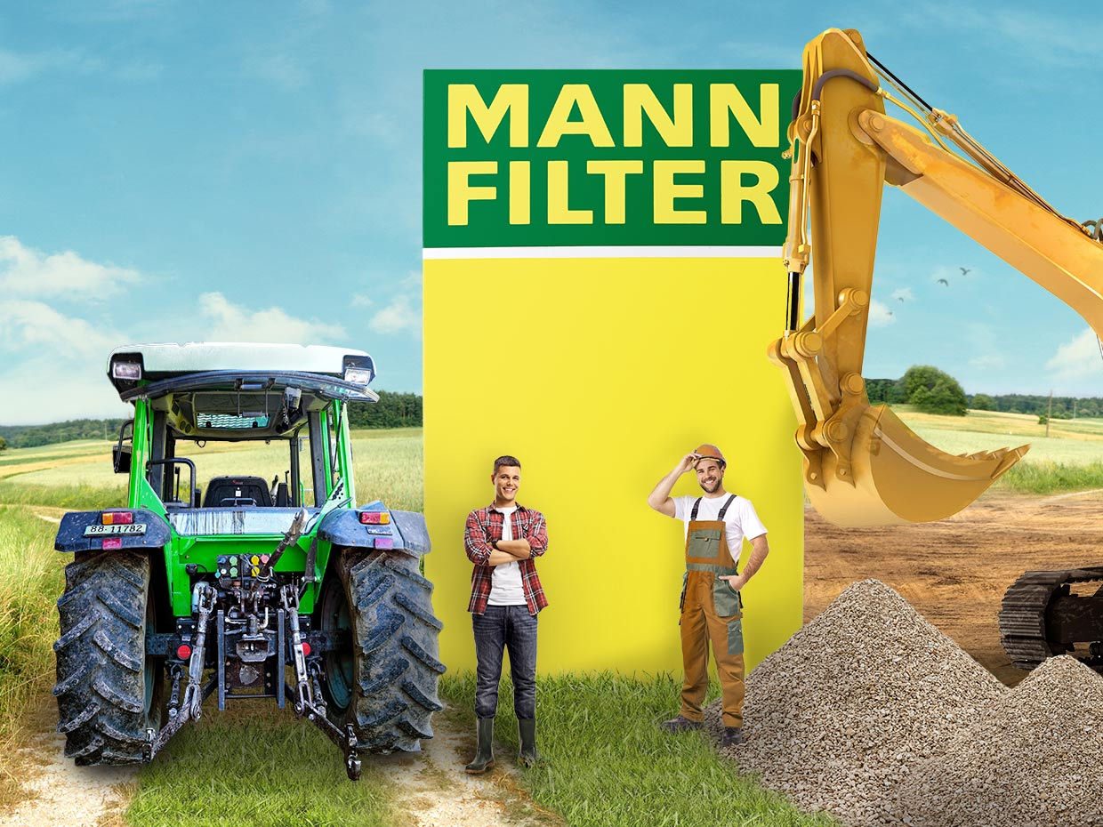 A green tractor, two men, and a yellow excavator on a field with a bright yellow MANN-FILTER logo