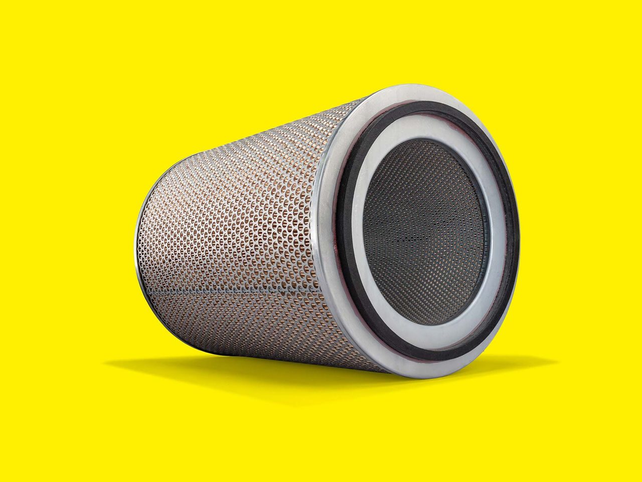 Cylindrical MANN-FILTER engine air filter with metal design on a yellow background