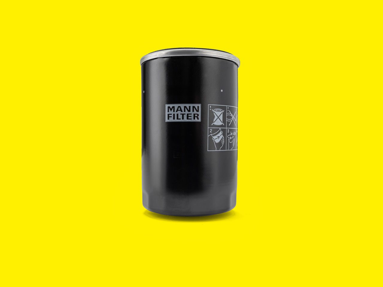 Black MANN-FILTER fuel filter with printed instructions on a bright yellow background