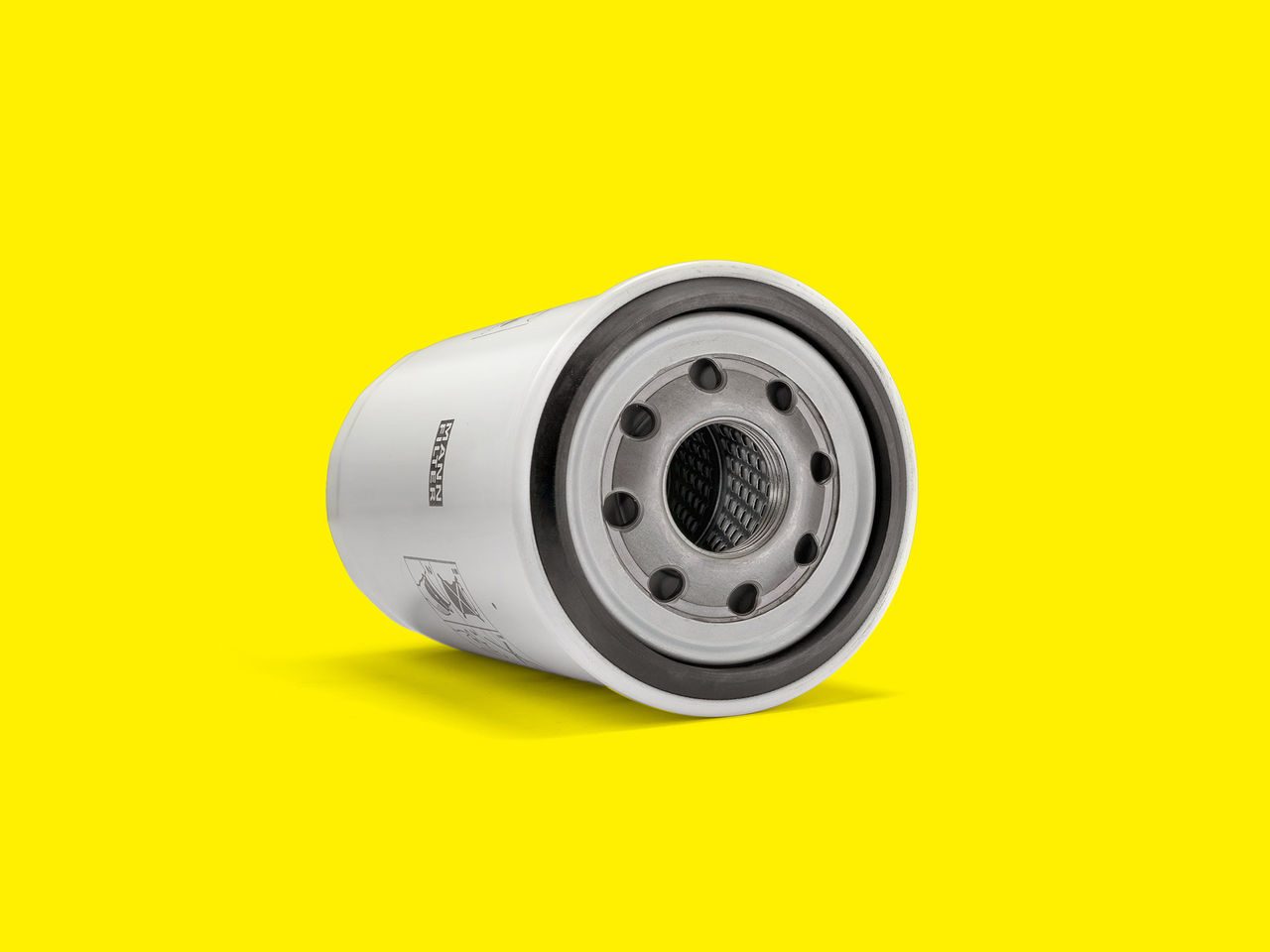 White MANN-FILTER oil filter with metal threaded base on a bright yellow background