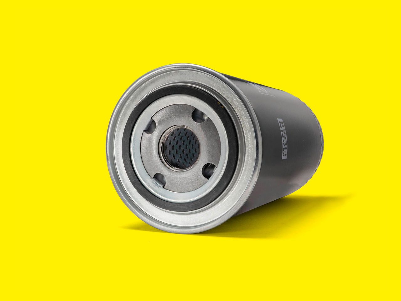 A black and silver oil filter for forklifts displayed horizontally on a bright yellow background
