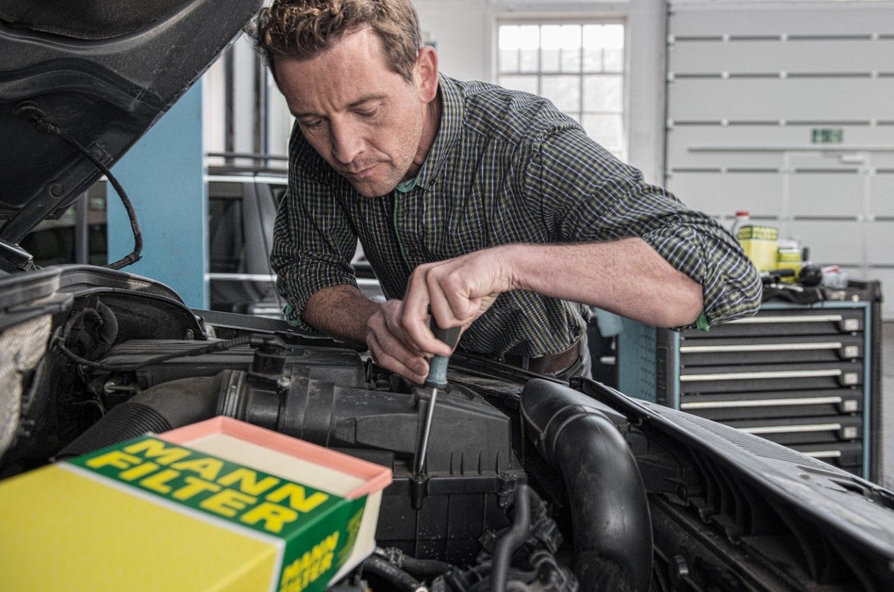 Garagiste MANN-FILTER installant un filtre à air moteur dans une voiture