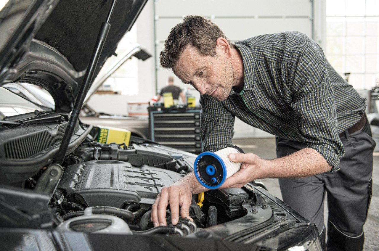 Garagiste MANN-FILTER installant un filtre à carburant dans une voiture