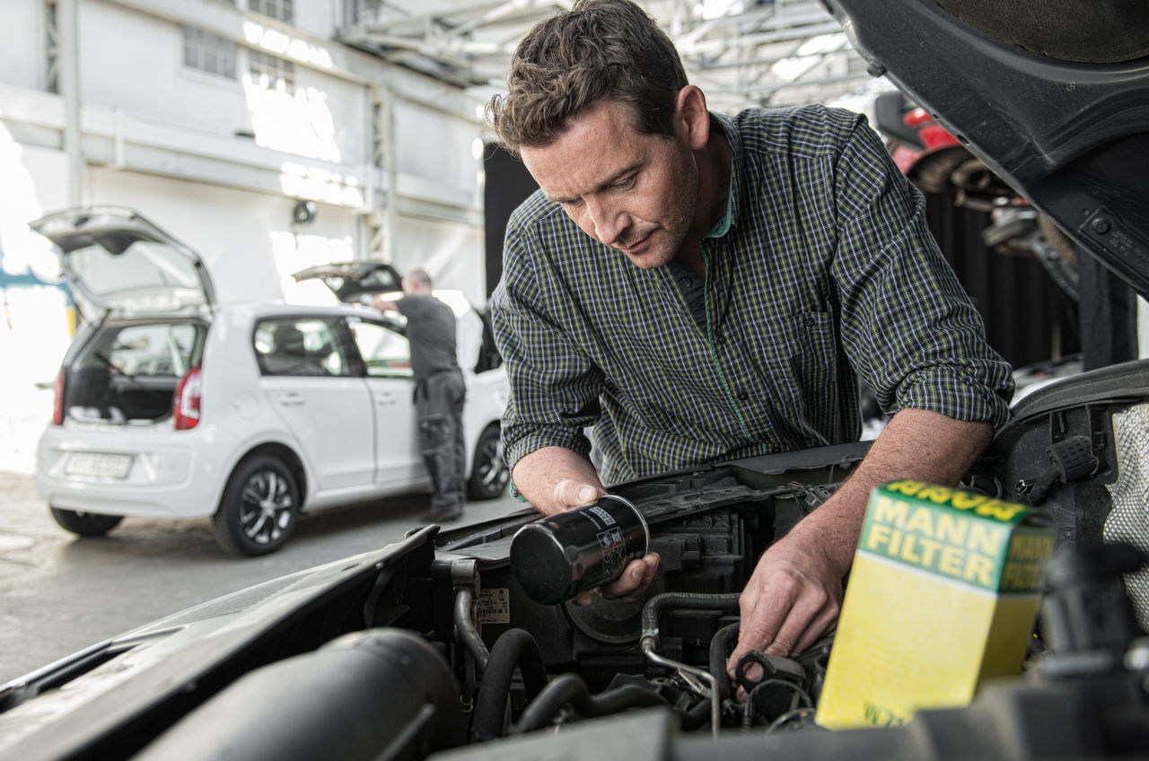 Workshop installing oil filter in car