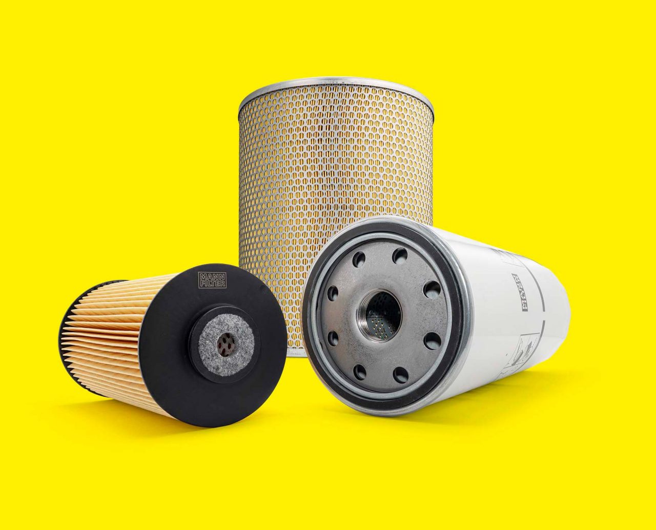 A selection of marine filters, including fuel, oil, and air filters, on a yellow background