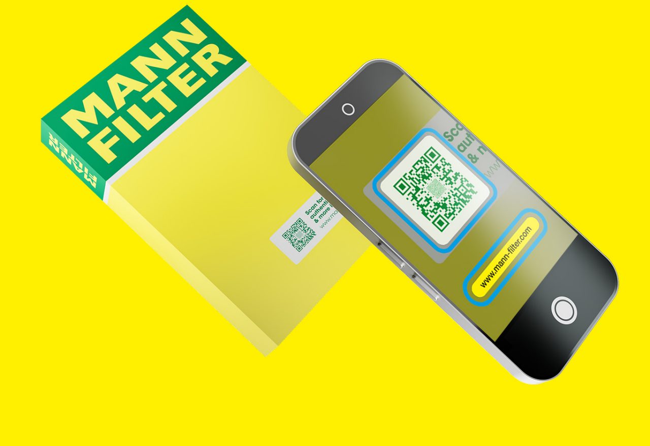 The Secure QR Code on a yellow-green MANN-FILTER packaging is scanned with a smartphone next to it