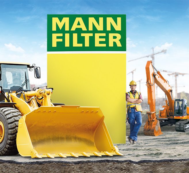 Yellow loader, worker, and excavator near MANN-FILTER branding at a construction site